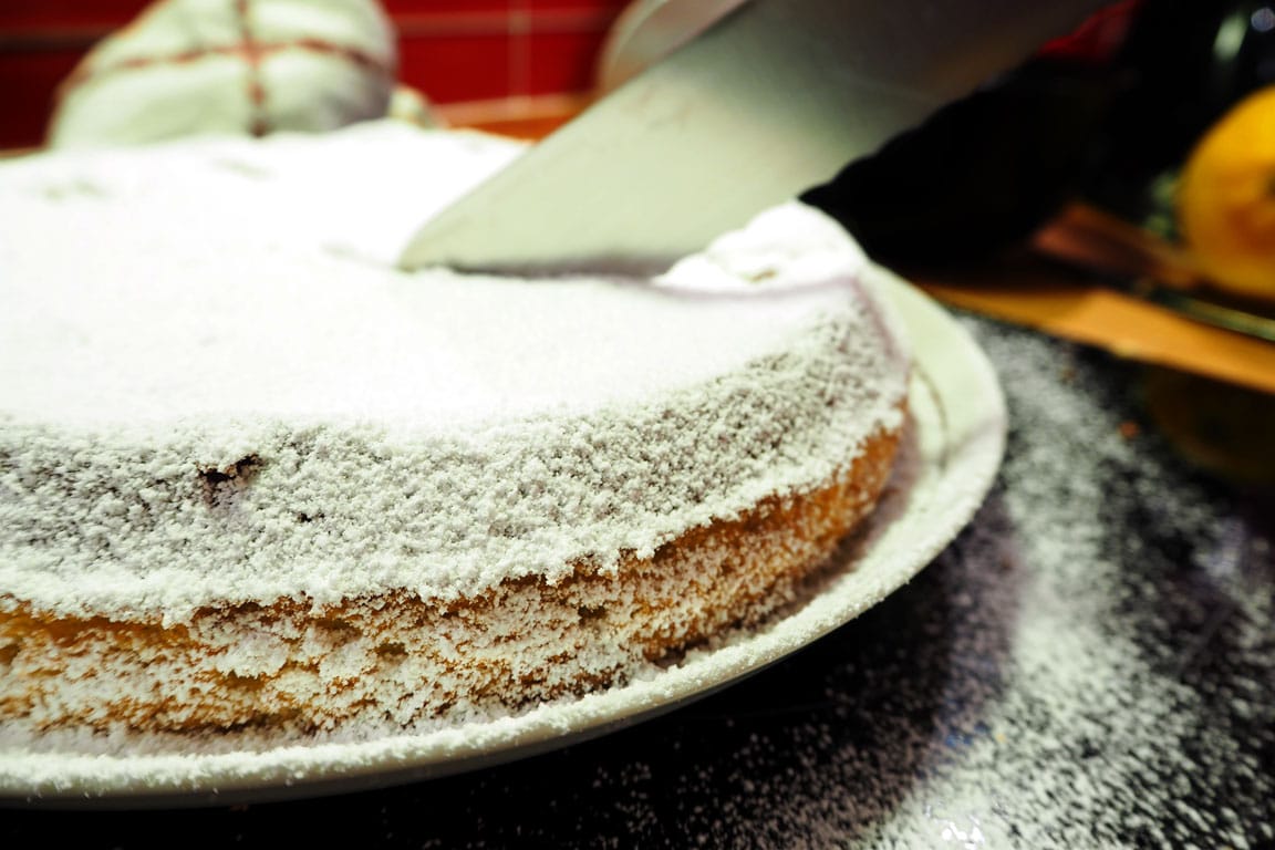 A knife cutting into a lemon and olive oil cake