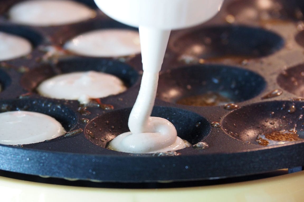 pouring the dough into the poffertjes iron