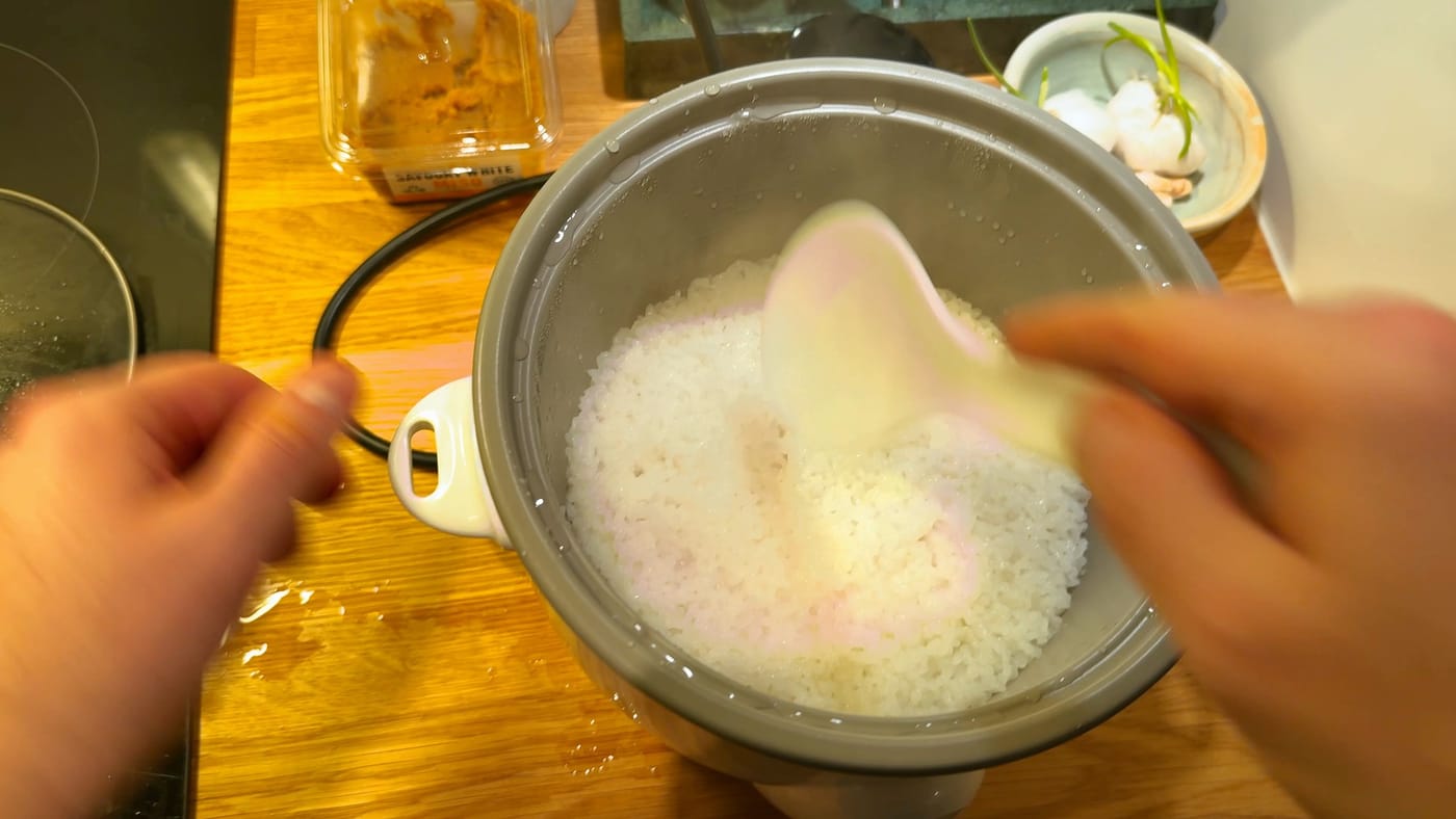 Fluffing the cooked rice with a paddle