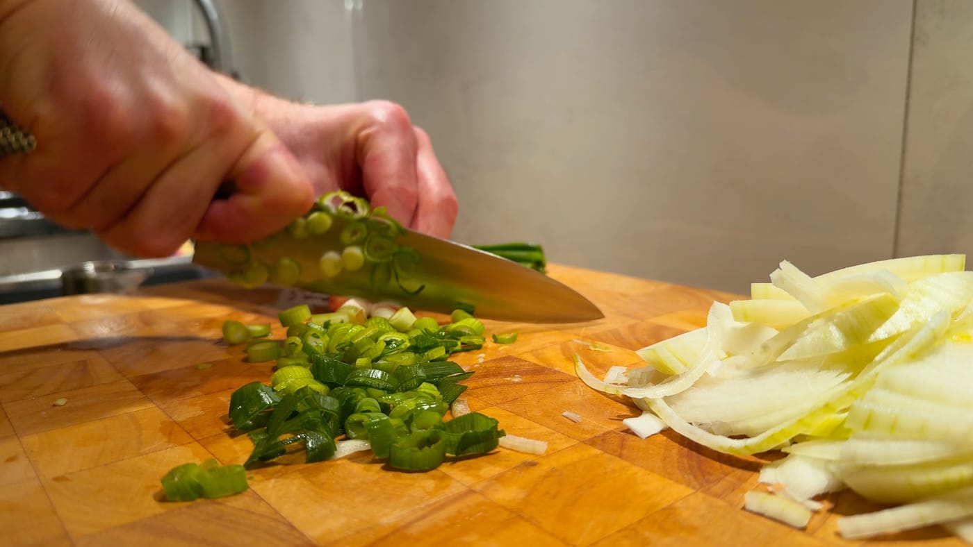 Chopped spring onions and sliced onion on the board